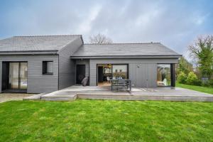 a gray house with a deck and a table at LE GRAIN DE CHARME - Maison contemporaine proche golfe du Morbihan in Sarzeau