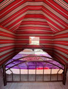 a bed in a room with a striped ceiling at Wadi Rum Pyramids Camp in Wadi Rum