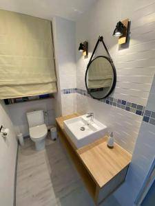 bagno con lavandino, servizi igienici e specchio di Joli appartement 4 personnes - vue mer a Ploemeur