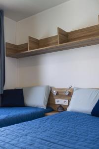 a bedroom with two beds with blue sheets and wooden shelves at Houseboat Floatart Experience Bisceglie in Bisceglie