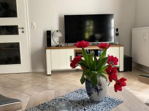 un jarrón con flores rojas sobre una mesa en la sala de estar en Villa Friedericia - Whg1, en Wyk auf Föhr