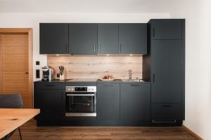 a kitchen with black cabinets and a sink at Avero Lodge in Samnaun