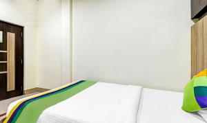 a bedroom with a white bed with a colorful pillow at Treebo Apollo in Guwahati