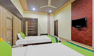 a bedroom with two beds and a flat screen tv at Treebo Apollo in Guwahati