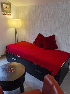 Schlafzimmer mit einem Bett mit roter Bettwäsche und einem Stuhl in der Unterkunft Obungalow de July Belle vue in Saint-Julien-sur-Calonne