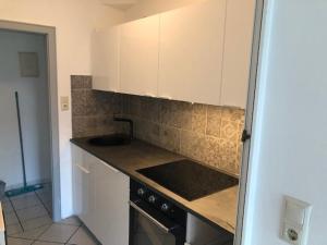 a kitchen with white cabinets and a sink and a stove at Haus Pamela Wohnung A in Neuharlingersiel