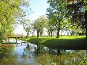 a river in a park with trees and a bridge at Hotel Am Markt Nordenham in Nordenham