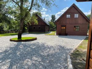 a barn with a tree in front of a driveway at Dwie Lipy Domy Wakacyjne in Złatna