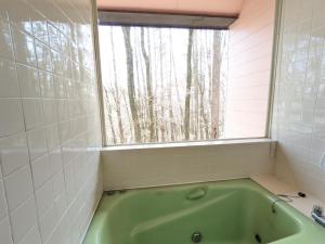 een badkamer met een groen bad en een raam bij Asuka's House 1 - Vacation STAY 30115v in Hokuto