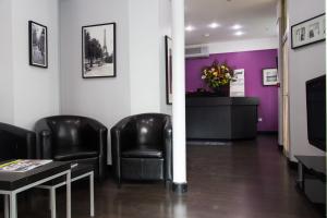 une salle d'attente avec des chaises noires et des murs violets dans l'établissement Hotel du Chemin Vert, à Paris