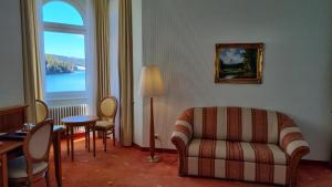 ein Wohnzimmer mit einem Sofa, einem Tisch und einem Fenster in der Unterkunft Seehotel Hubertus in Schluchsee