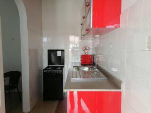 a small kitchen with red cabinets and a sink at Cheerful and spacious 1-bedroom house in Kumasi