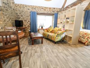 a living room with a couch and a bed and a tv at The Forge at Smithy Cottage in Bloxham