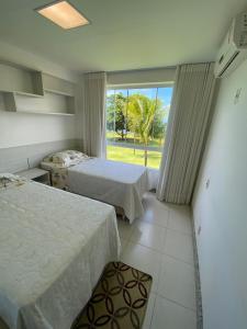 um quarto com 2 camas e uma grande janela em Paraíso dos corais Pe na areia em Guarajuba