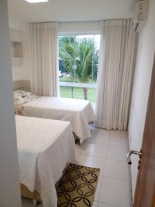 zwei Betten in einem Zimmer mit Fenster in der Unterkunft Paraíso dos corais Pe na areia in Guarajuba + 28 Fotos