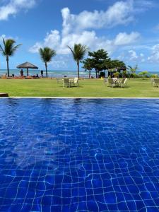 - une piscine à côté d'une plage bordée de palmiers dans l'établissement Paraíso dos corais Pe na areia, à Guarajuba