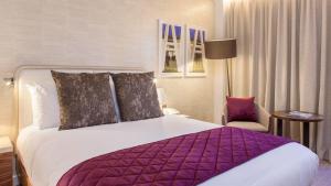 Pokój hotelowy z dużym łóżkiem i krzesłem w obiekcie Crowne Plaza London Kings Cross, an IHG Hotel w Londynie