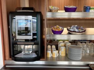 une machine à café assise sur une étagère avec des assiettes dans l'établissement Kyriad Dol-de-Bretagne, à Dol-de-Bretagne