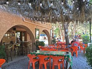 an outdoor restaurant with orange chairs and tables and people sitting at Camping Paduella in Calvi