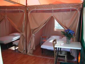 a room with two beds and a table in a tent at Camping Paduella in Calvi