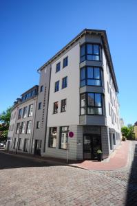 un gran edificio blanco en una calle adoquinada en The Green Rostock Apartment Hotel en Rostock