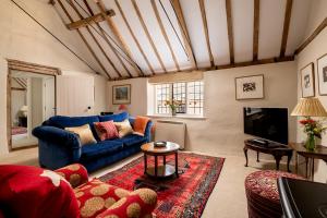 a living room with a blue couch and a tv at The Stables in Kings Cliffe
