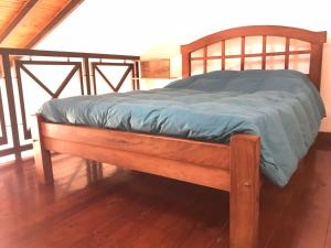 a wooden bed with a blue blanket on a wooden floor at Loft 5ta sección Mendoza in Mendoza
