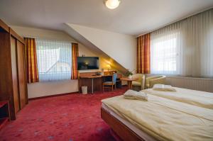 una camera d'albergo con due letti, una scrivania e una televisione di AVALON Hotelpark Königshof a Königslutter am Elm