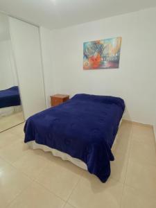 ein Bett mit einer blauen Decke in einem Zimmer in der Unterkunft Departamento de 2 dormitorios con asador in Santiago del Estero