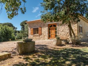 a stone house with a wooden door in a yard at Holiday Home Domaine La Batisse by Interhome in Lespignan