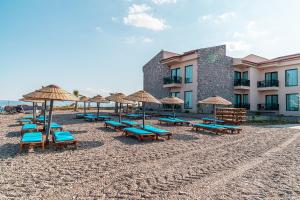 a group of chairs and umbrellas on a beach at Assos Dove Hotel Resort & SPA in Behramkale