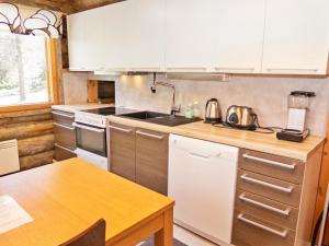 ルカにあるHoliday Home Rukaveska 4a by Interhomeの白いキャビネットと木製テーブル付きのキッチン