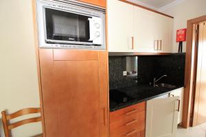 eine Küche mit einer Mikrowelle auf einem Holzschrank in der Unterkunft Waves View- Albufeira in Albufeira