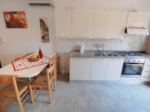 una cucina con armadi bianchi, tavolo e lavandino di Apartment Simma-9 by Interhome a Bibione