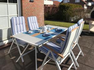 a table with two chairs and a table with cups and plates at Holiday Home Sandmuschel by Interhome in Norddeich