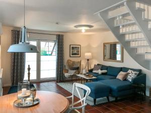 a living room with a blue couch and a staircase at Holiday Home Sandmuschel by Interhome in Norddeich