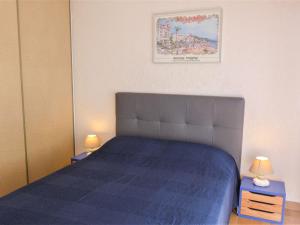 a bedroom with a bed with a blue bedspread and two lamps at Apartment Cabourg Beach by Interhome in Cabourg