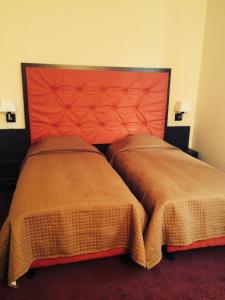 Oţelu RoşuにあるHotel Fiamaのベッドルーム1室(大きなオレンジ色のヘッドボード、ベッド2台付)