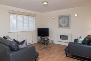 a living room with two couches and a tv at 1 Eureka Mews in Chester-le-Street