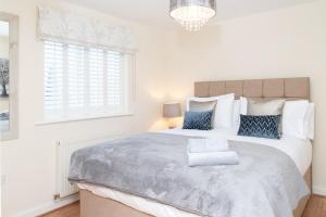 a white bedroom with a large bed with blue pillows at 1 Eureka Mews in Chester-le-Street