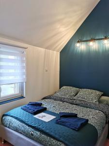 Schlafzimmer mit einem Bett mit blauer Bettwäsche und einem Fenster in der Unterkunft Le 5 in Plouézec