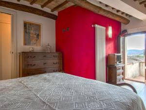 1 dormitorio con pared roja, cama y ventana en Holiday Home Casa Francesca by Interhome, en Rosia