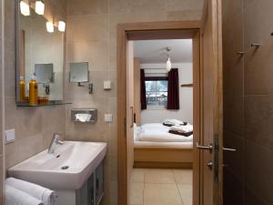 Un baño con lavabo, espejo y cama. en Apartment Mountain Resort C15 by Interhome, en Kaprun