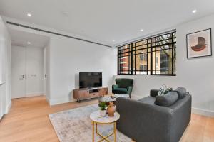 ein Wohnzimmer mit Sofa und Fernseher in der Unterkunft Whitfield Street Residences by Aeria Apartments in London