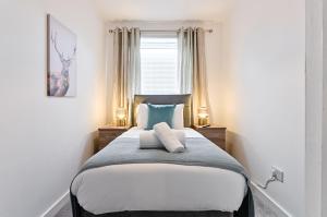 Un dormitorio con una cama con dos lámparas y una ventana. en Spacious 3 Bed - Smart TVs - Great for Work Stays, en Swansea