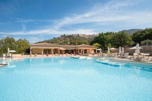 a large swimming pool with chairs and a building at OasiMaremma Village in Scarlino