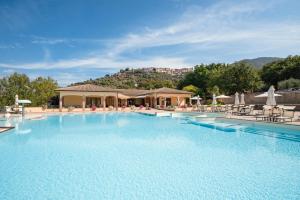 una gran piscina con sillas y un edificio en OasiMaremma Village, en Scarlino