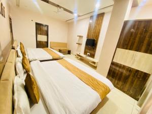 a bedroom with two beds and a flat screen tv at Hotel Motherland in Barwāh +28 photos