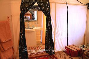 een kamer met een bed met een spiegel en een wastafel bij Luxury Tented Erg Chebbi in Merzouga