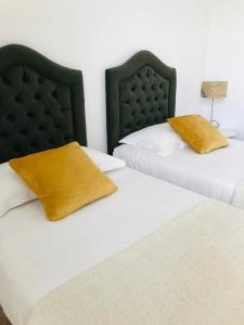 two beds with black and white sheets and yellow pillows at résidence les oliviers in Soliman